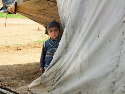 A young boy standing in front of a tent evokes the stark realities of displacement, a poignant connection to Myanmar’s ongoing humanitarian crisis, by Salah Darwish via Unsplash, July 23, 2024, https://unsplash.com/photos/a-young-boy-standing-in-front-of-a-tent-Wti2okH2uvA