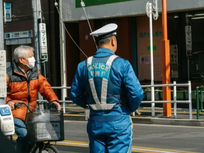 A japanese police officer stands on a crosswalk.